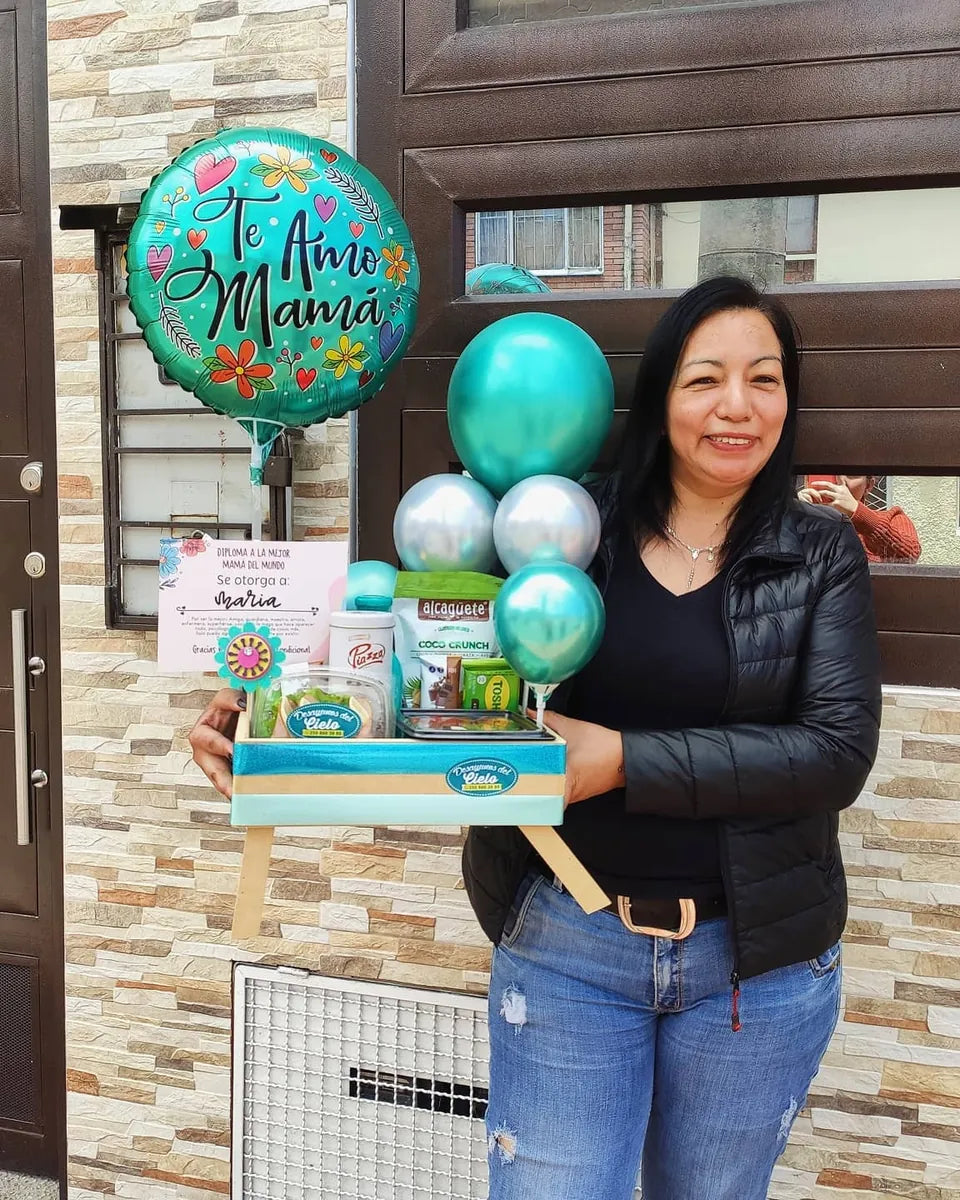 Mujer feliz recibe su regalo con globos frente a la puerta de su casa