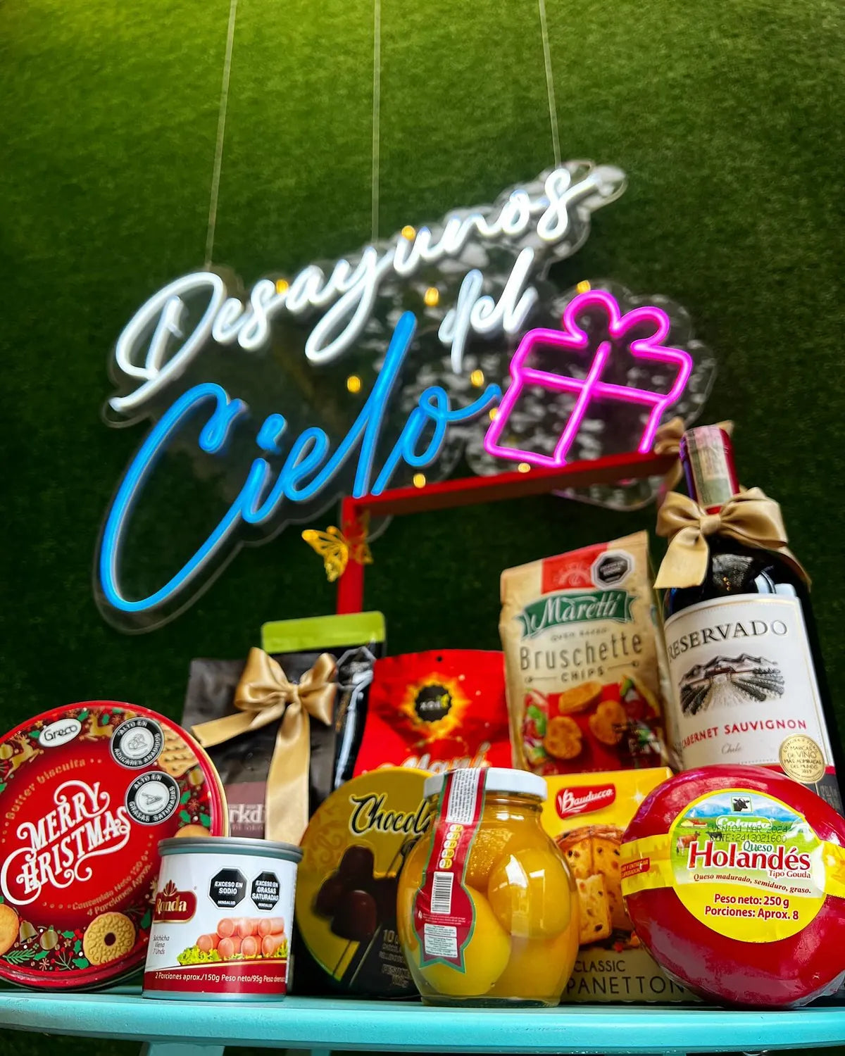 Ancheta navideña con vino, quesos y dulces junto al letrero de Desayunos del Cielo